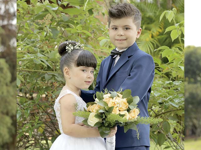 Daminha - O modelo da daminha de honra segue um modelo clássico com brilho próprio do tecido zibeline, organza cristal e costas com botões forrados. Pajem - O terno do pajem na cor Azul Bic faz parte 