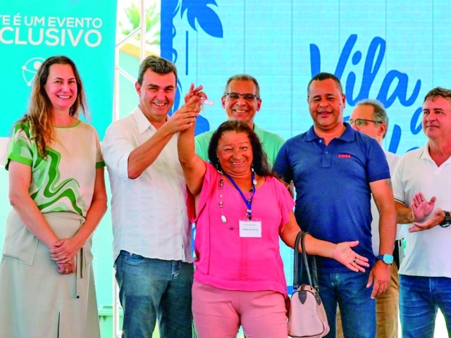 Maria da Silva, uma das contempladas, recebendo sua chave pelas mãos das autoridades locais 