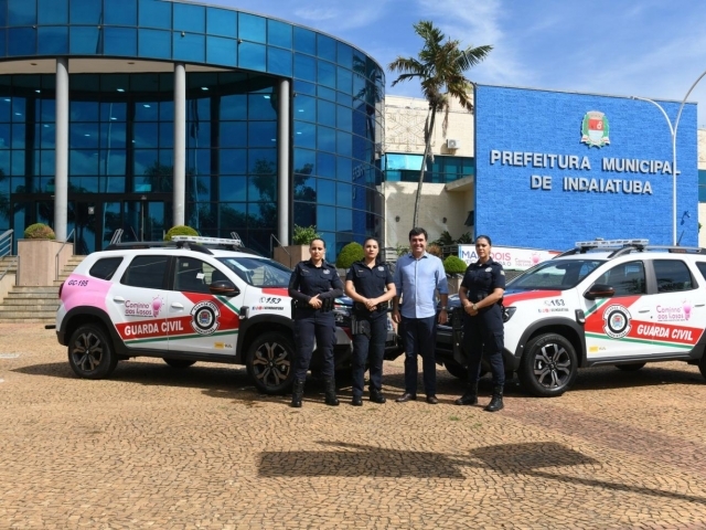 Prefeito Dr. Custódio Tavares com três agentes da Guarda Civil, entre viaturas do programa Caminho das Rosas